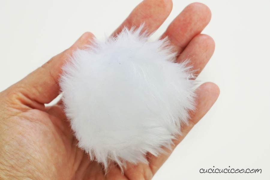 hand holding white fur pom pom